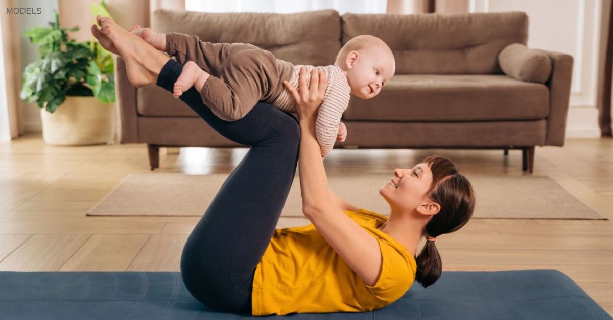Woman laying on yoga mat with baby in her arms (MODELS)